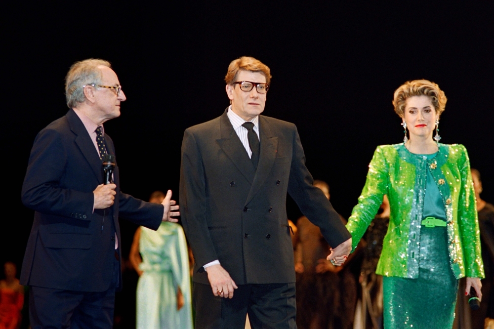 French businessman Pierre Berge (L), co-founder of Yves Saint Laurent Couture House, welcomes French fashion designer Yves Saint-Laurent (C) and French actress Catherine Deneuve during the show celebrating the 30th anniversary of the creation of the Yves Saint-Laurent House at the Bastille Opera in Paris in this file photo. — AFP
