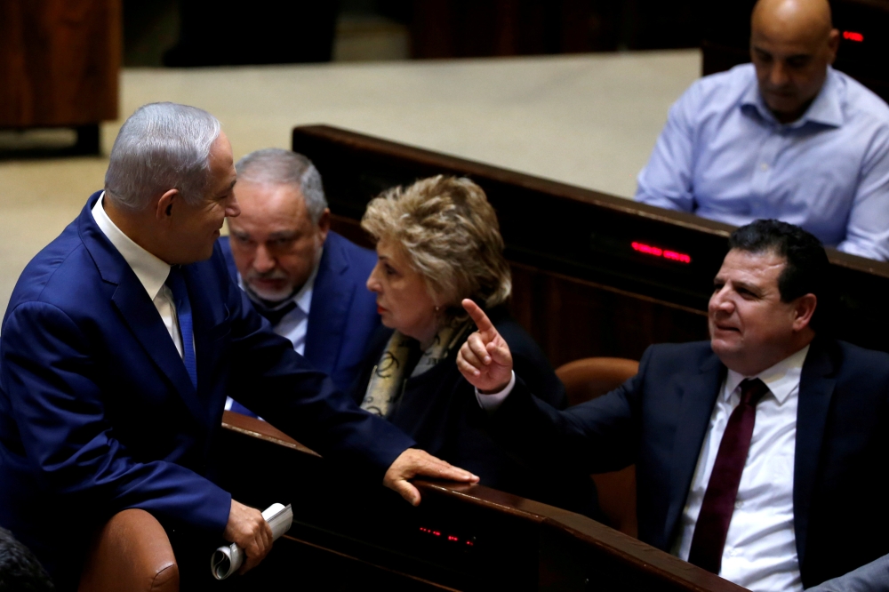


Israeli Prime Minister Benjamin Netanyahu chats with Ayman Odeh, head of the Joint Arab List, in the plenum at the Knesset, Israel›s parliament, in occupied Jerusalem, recently. — Reuters
