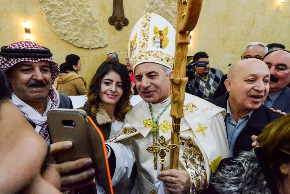 New Chaldean Catholic Archbishop Najib Michaeel Moussa, center, uses a cell phone to take a “selfie” photograph with a woman during his ordination ceremony at St Paul’s Cathedral in the eastern part of the northern Iraqi city of Mosul on Friday. — AFP