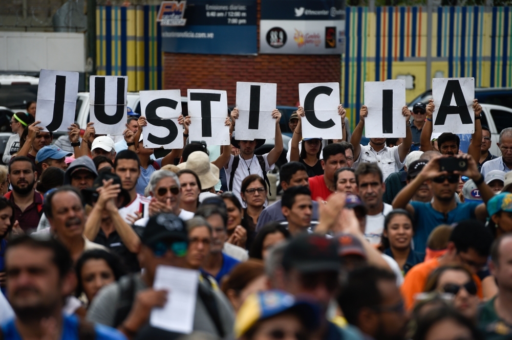 Venezuelan opposition supporters holding up letters reading 