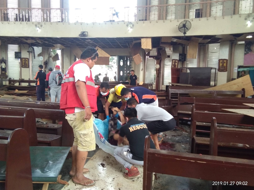 Members of the Philippine Red Cross attend to a casualty inside a church after a bombing attack in Jolo, Philippines, Sunday.  — Reuters