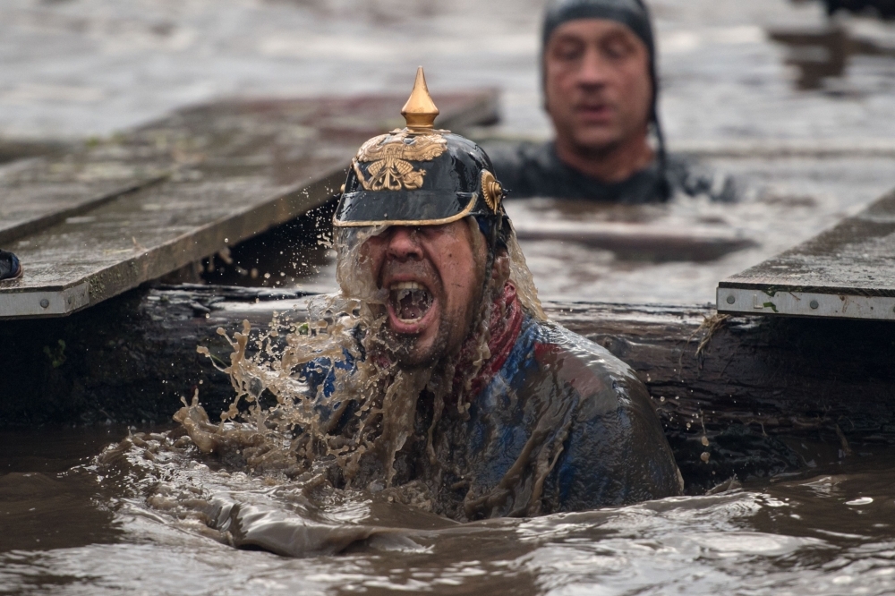 A competitor emerges from muddy water as he negotiates a water obstacle in the Tough Guy endurance event near Wolverhampton, central England. — AFP