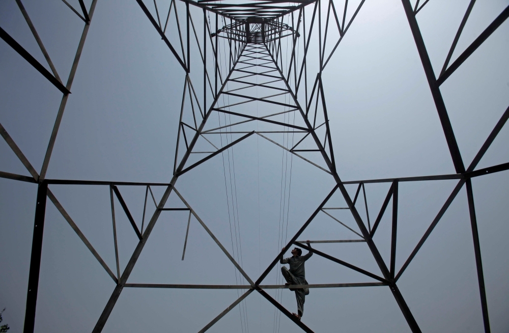 A worker of Peshawar Electric Supply Company (PESCO) climbs up a high-voltage pylon in Peshawar, Pakistan, in this Aug. 7, 2017 file photo. — Reuters