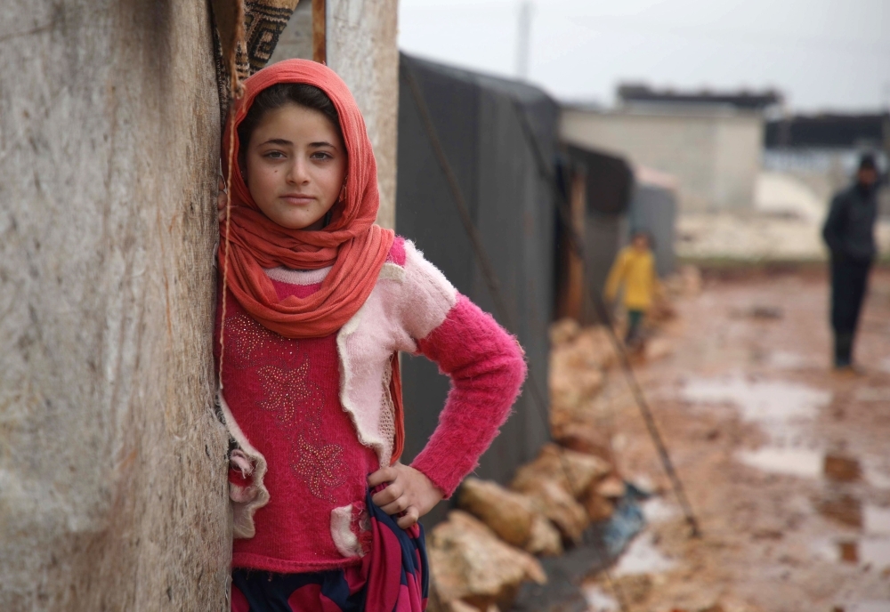 A displaced Syrian girl stands in the entrance of a tent at the Qah camp for the displaced along the Turkish border in the northwestern province of Idlib, on Thursday. — AFP