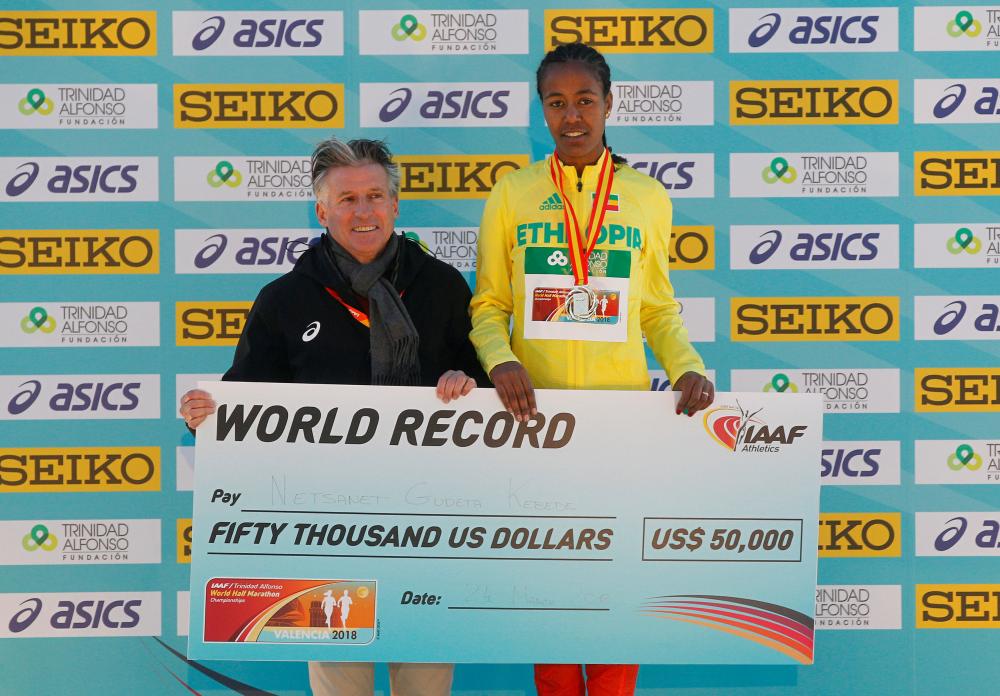 File photo shows IAAF President Sebastian Coe presenting Ethiopia's Netsanet Gudeta Kebede with a check after she won the women's race and setting a new world record in the IAAF World Half Marathon Championships. — Reuters