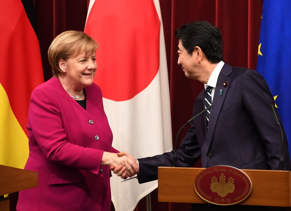 German Chancellor Angela Merkel (L) shakes hands with Japanese Prime Minister Shinzo Abe (R) at the end of a joint press conference following their meeting at Abe's official residence in Tokyo on Monday. — AFP
