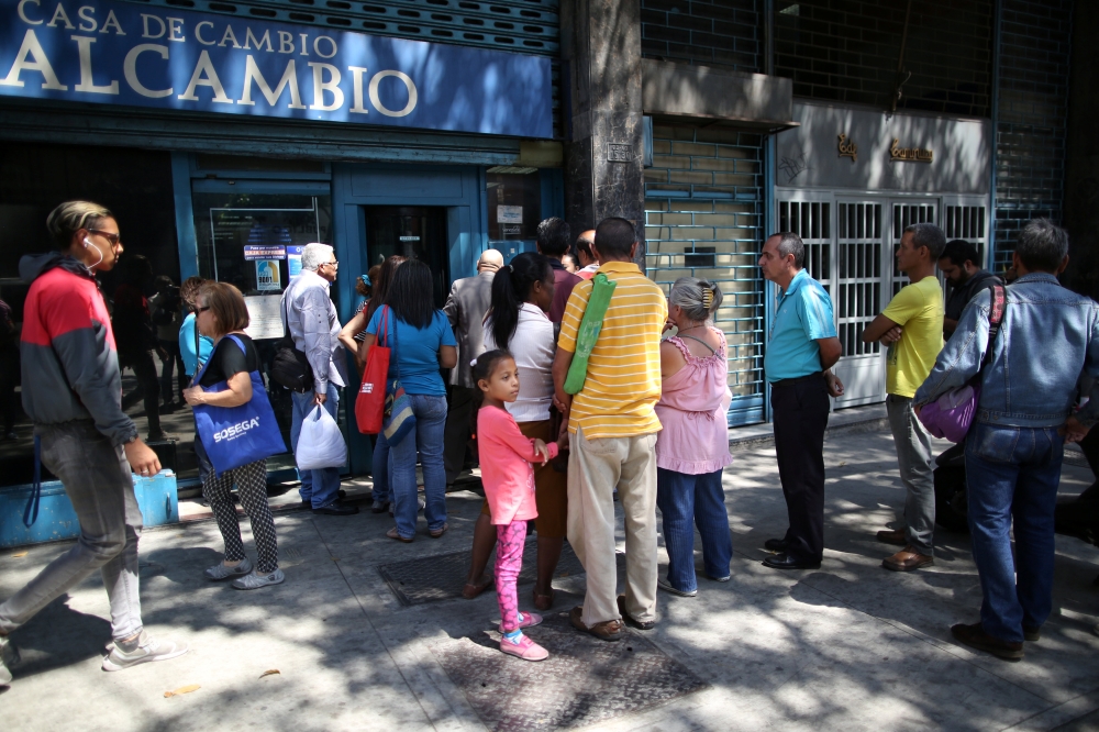 People wait in line outside of a currency exchange house in Caracas, Venezuela, Tuesday. — Reuters