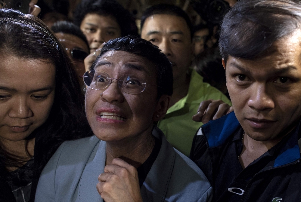 Philippine journalist Maria Ressa, center, arrives at a regional trial court in Manila to post bail on Thursday. — AFP