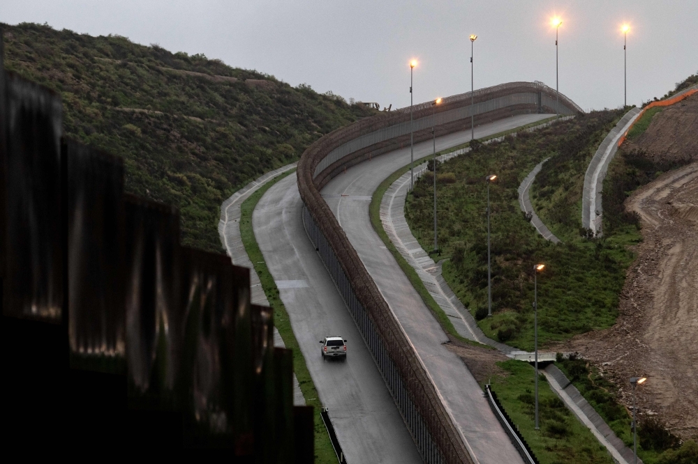 A Border Patrol unit drives near a section of reinforced US-Mexico border fence seen from Tijuana, Baja California state, Mexico, on Thursday. — AFP