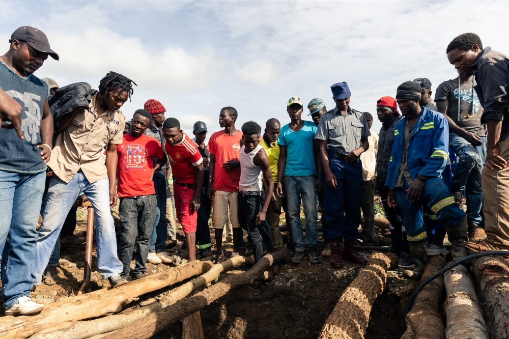 Fellow miners look down a pit during a mine search and rescue operation at Cricket Mine in Kadoma, Mashonaland West Province where more than 23 miners are trapped underground and feared dead, on Friday. — AFP
