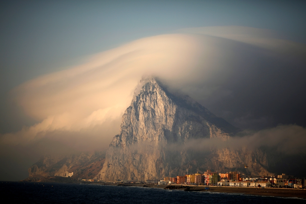 A cloud partially covers the tip of the Rock of the British territory of Gibraltar at sunrise from La Atunara port before Spanish fishermen sail in their fishing boats with their relatives to take part in a protest at an area of the sea where an artificial reef was built by Gibraltar using concrete blocks, in Algeciras bay, La Linea de la Concepcion in southern Spain in this Aug.18, 2013 file photo. — Reuters