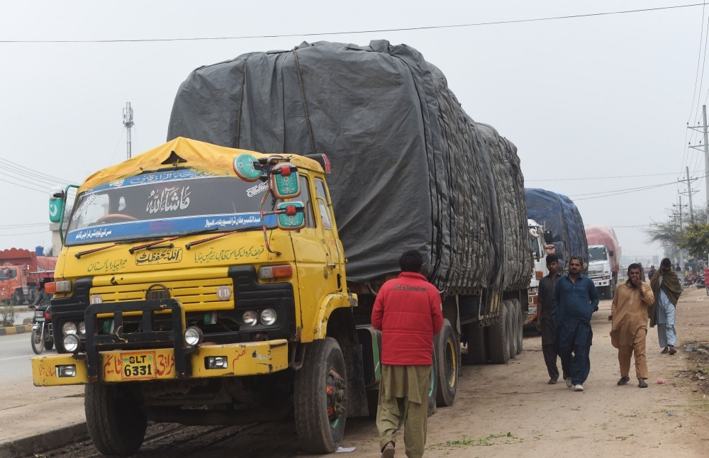 Pakistani drivers walk next to loaded trucks parked along a road near the Wagah border between Pakistan and India on Wednesday, following the withdrawn of trade privileges for Pakistan by the Indian government. — AFP