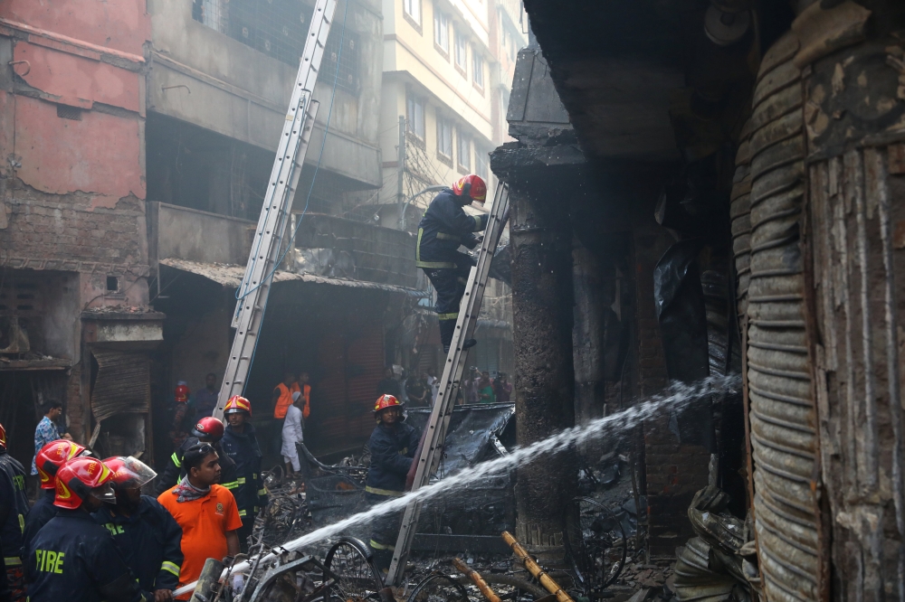Firefighters work outside a burned warehouse in Dhaka, Bangladesh, on Thursday. — Reuters