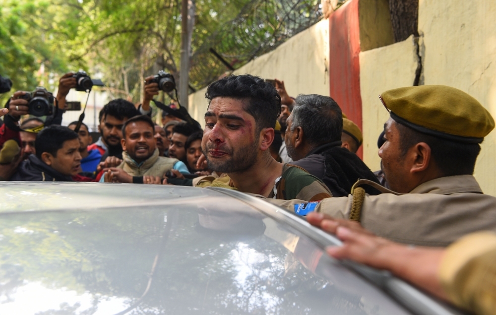 An injured man, center, that an angry mob had attacked, believing him to be a Kashmiri who had allegedly shouted pro-Pakistan slogans, is shielded by Indian policemen in New Delhi in this Feb. 17, 2019 file photo. — AFP
