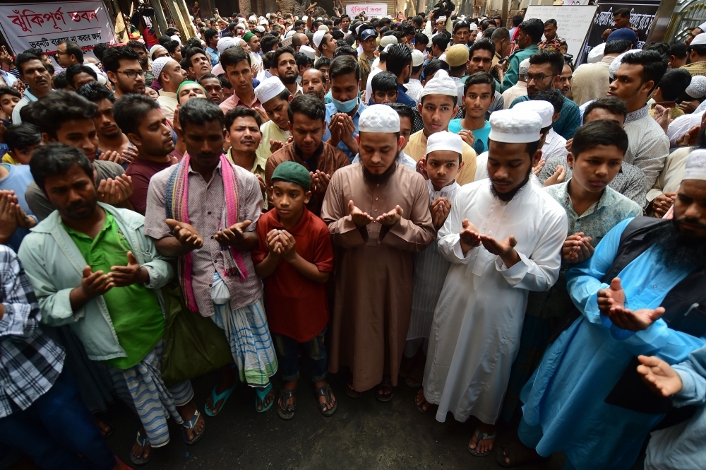 Bangladeshi Muslims pray for the victims of a fire in Dhaka on Friday. — AFP