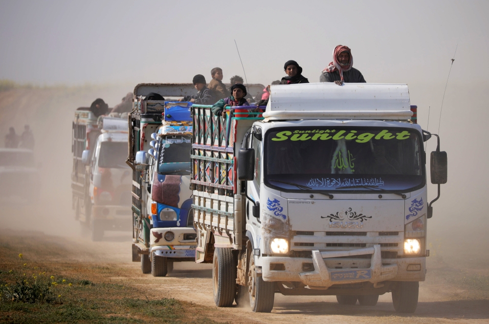 Trucks loaded with civilians ride near the village of Baghouz, Deir Al Zor province, Syria, on Friday. — Reuters