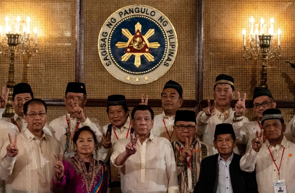 Philippine President Rodrigo Duterte, front center, gives a peace sign with Moro Islamic Liberation Front (MILF) chairman Murad Ebrahim, front third right, during the Ceremonial Confirmation of the Bangsamoro Organic Law Plebescite Law Canvass Results and Oath-taking of Transition Authority at the Malacanang palace in Manila on Friday. — AFP