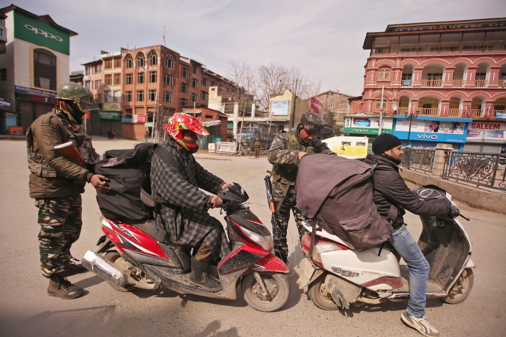 Indian Central Reserve Police Force (CRPF) personnel check the bags of scooterists during restrictions after Kashmiri separatist on Sunday called for shutdown to protest the arrest of their leaders in Srinagar. — AFP