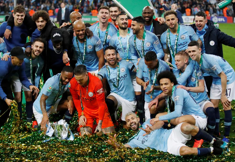 Manchester City's Raheem Sterling, Ederson and teammates pose with the trophy after beating Chelsea in the Carabao Cup (League Cup) final at Wembley Stadium in London Sunday. — Reuters