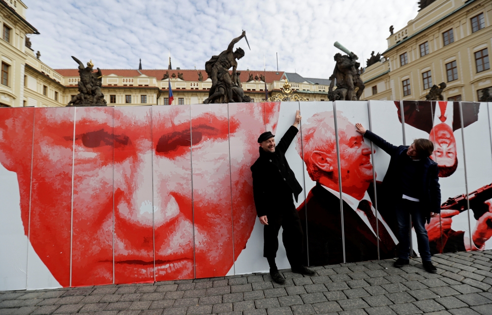 People pose in front of a paper wall depicting Russian President Vladimir Putin and Czech President Milos Zeman during a flash mob event in front of Prague Castle in Prague, Czech Republic, on Sunday. — Reuters