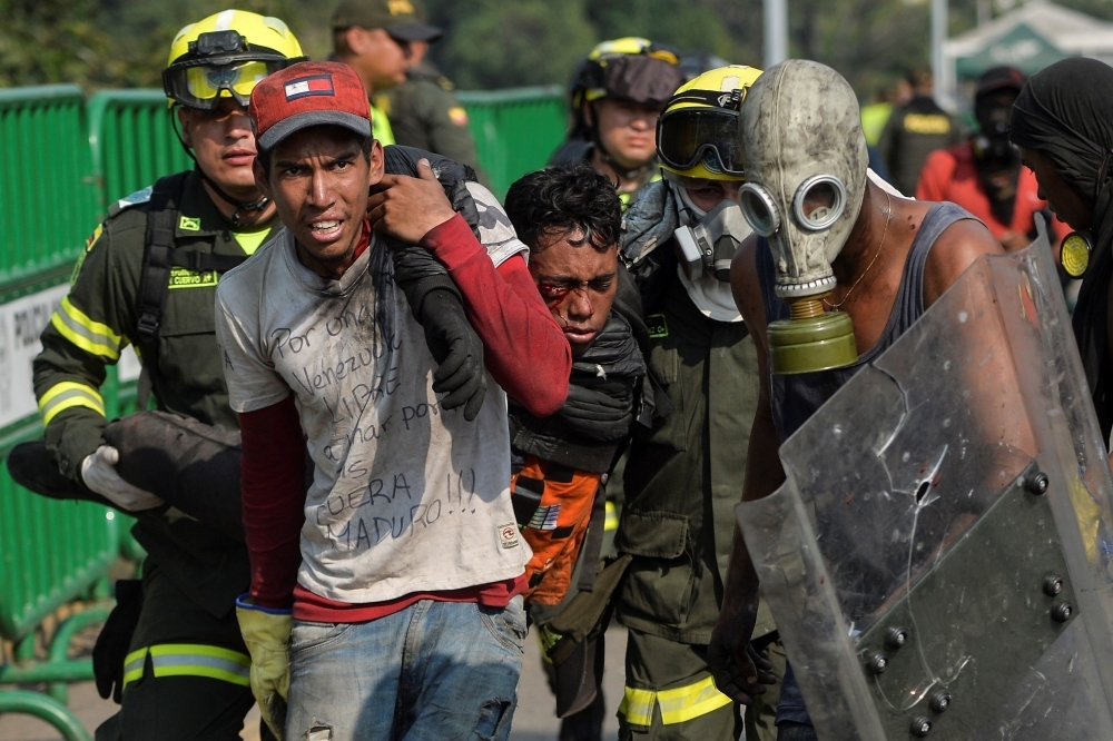 A demonstrator is being assisted on the Simon Bolivar International Bridge in Cucuta, Colombia, after being wounded during clashes with Venezuelan security forces across the border in San Antonio del Tachira, Venezuela, on Monday. — AFP