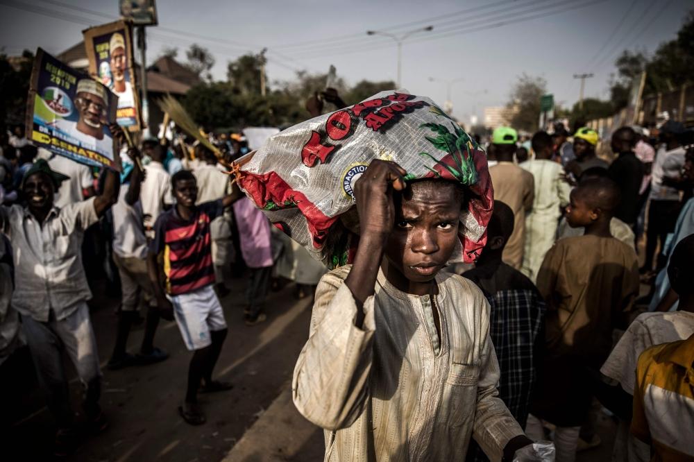 A boy cover himself with a plastic bag while All Progressives Congress Party (APC) supporters celebrate initial results released by the Nigerian Independent National Electoral Commission (INEC) in Kano, on Monday, two days after general elections. — AFP 