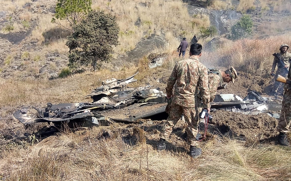 Pakistani soldiers stand next to what Pakistan says is the wreckage of an Indian fighter jet shot down in Pakistan controlled Kashmir at Somani area in Bhimbar district near the Line of Control on Wednesday. — AFP