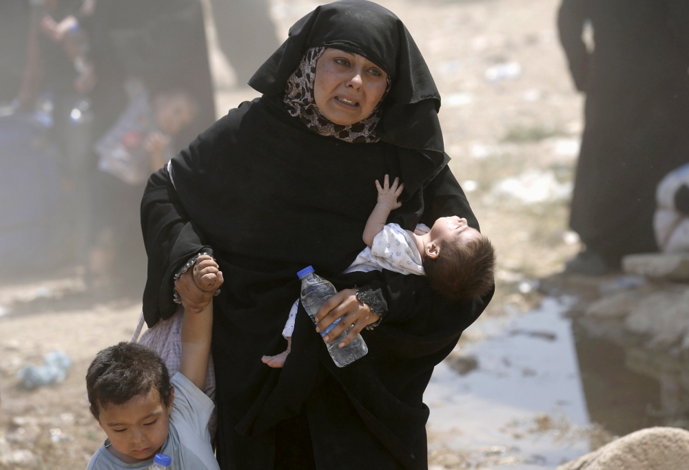 A Syrian refugee woman crosses into Turkey with her children at the Akcakale border gate in Sanliurfa province, Turkey in this file photo