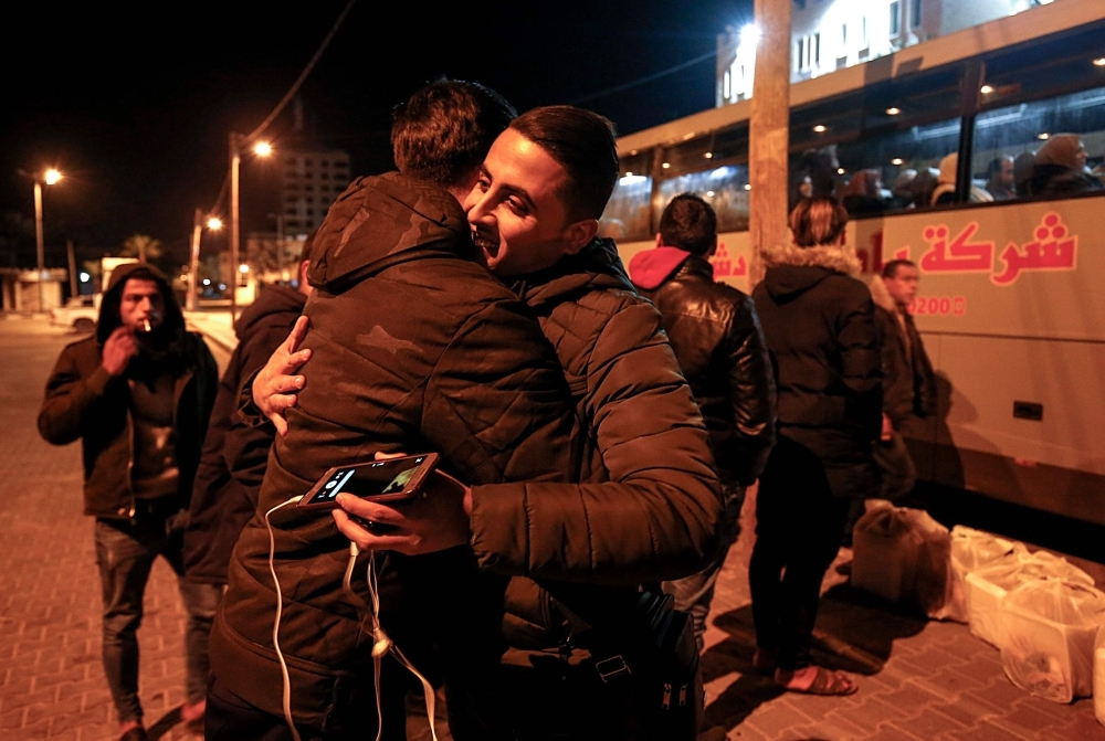 A Palestinian hugs a relative prior to boarding a bus at the Rafah border crossing between the Gaza Strip and Egypt on Sunday before crossing to depart for the holy city of Makkah to perform Umrah for the first time since 2014. — AFP