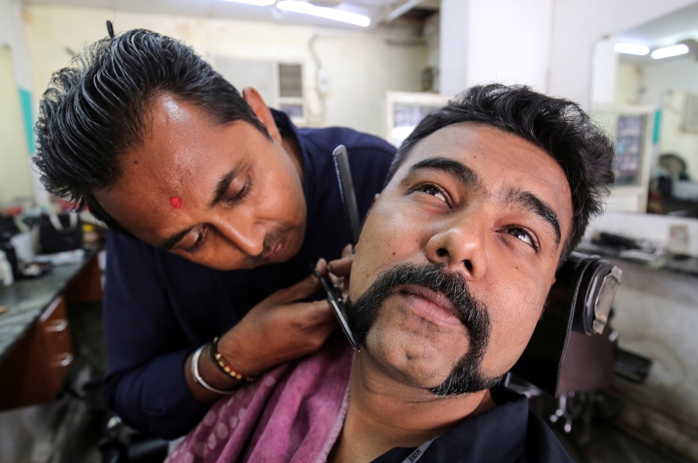 Dhiren Makvana gets his mustache trimmed similar to the one sported by Indian Air Force pilot Abhinandan Varthaman, who was captured and later released by Pakistan, inside a salon in Ahmedabad, India, on Monday. — Reuters