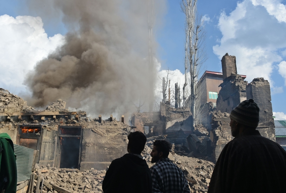 Kashmiri villagers look on a fire razes a house following a deadly gun battle between militants and Indian government forces in Tral area of Pulwama district, south of Srinagar, on Tuesday. — AFP