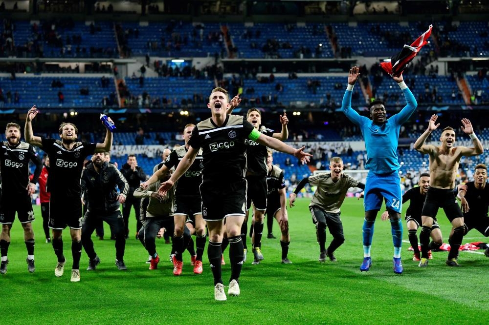 Ajax’s players celebrate at the end of the UEFA Champions League round of 16 second leg football match against Real Madrid at the Santiago Bernabeu Stadium in Madrid Tuesday. — AFP 