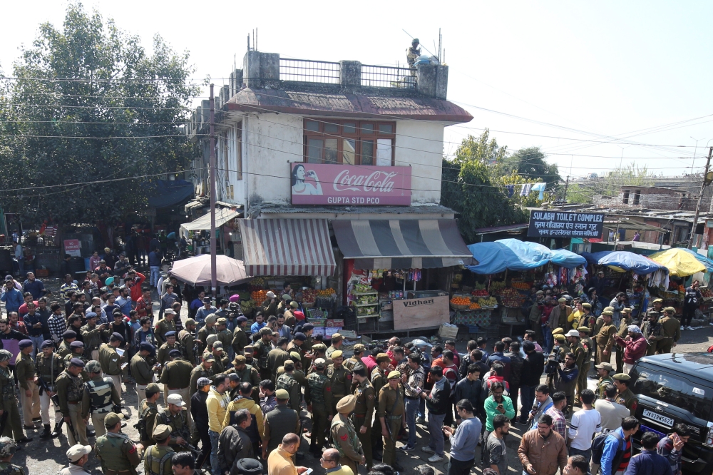 Policemen and onlookers stand at the site of a grenade blast in Jammu, India, on Thursday. — Reuters