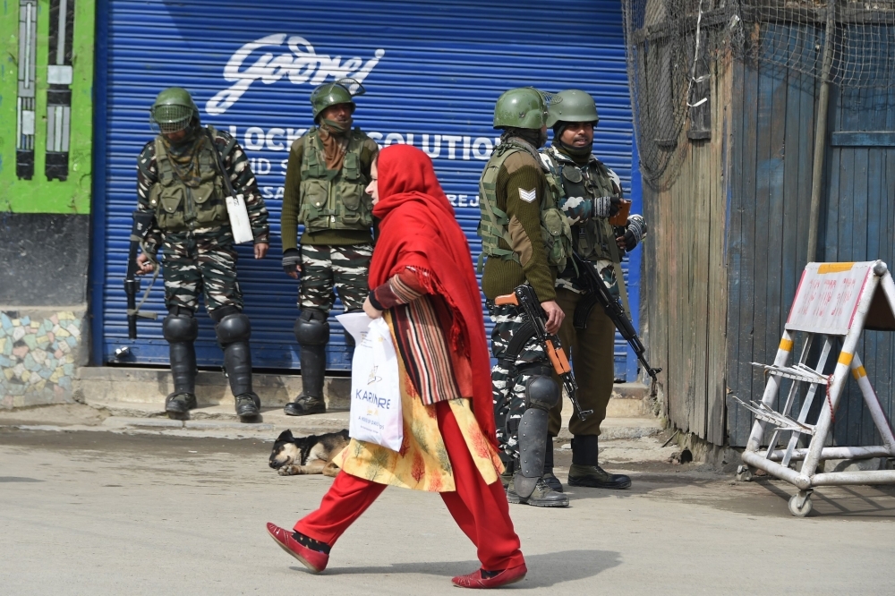 Indian paramilitary troopers stand guard in front of a closed shop as a Kashmiri resident walks along a street during a shutdown at Maisuma locality of Srinagar on Thursday, in reaction to the transfer of Kashmir Liberation Front (JKLF) chief Yasin Malik to a jail in Jammu. — AFP