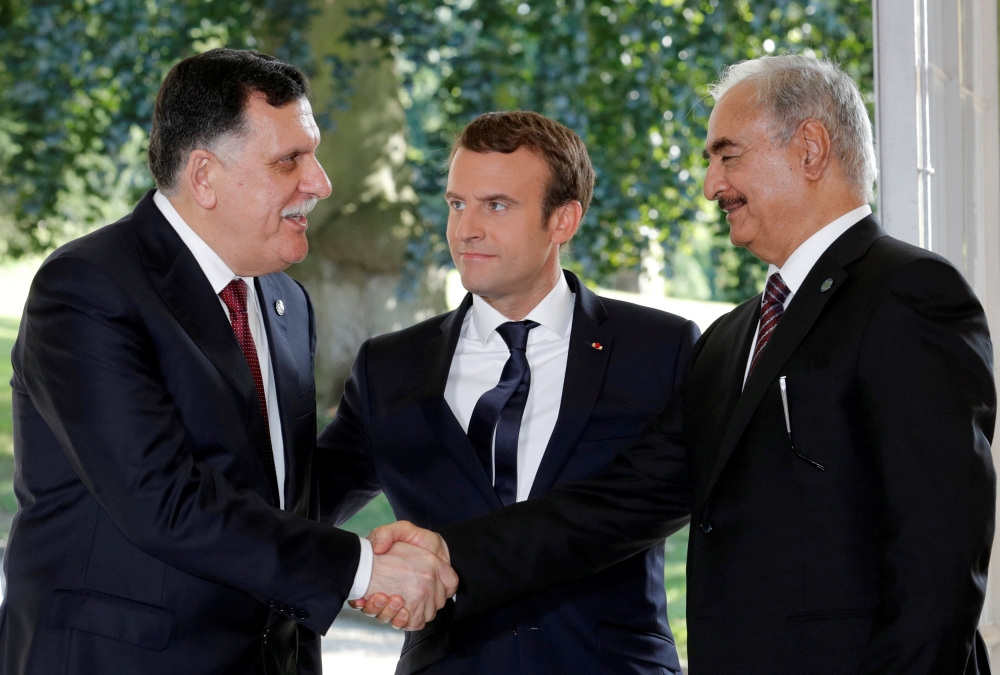 French President Emmanuel Macron stands between Libyan Prime Minister Fayez Al-Serraj, left, and General Khalifa Haftar, right, commander in the Libyan National Army (LNA), who shake hands after talks over a political deal to help end Libya’s crisis in La Celle-Saint-Cloud near Paris, France, in this July 25, 2017 file photo. — Reuters