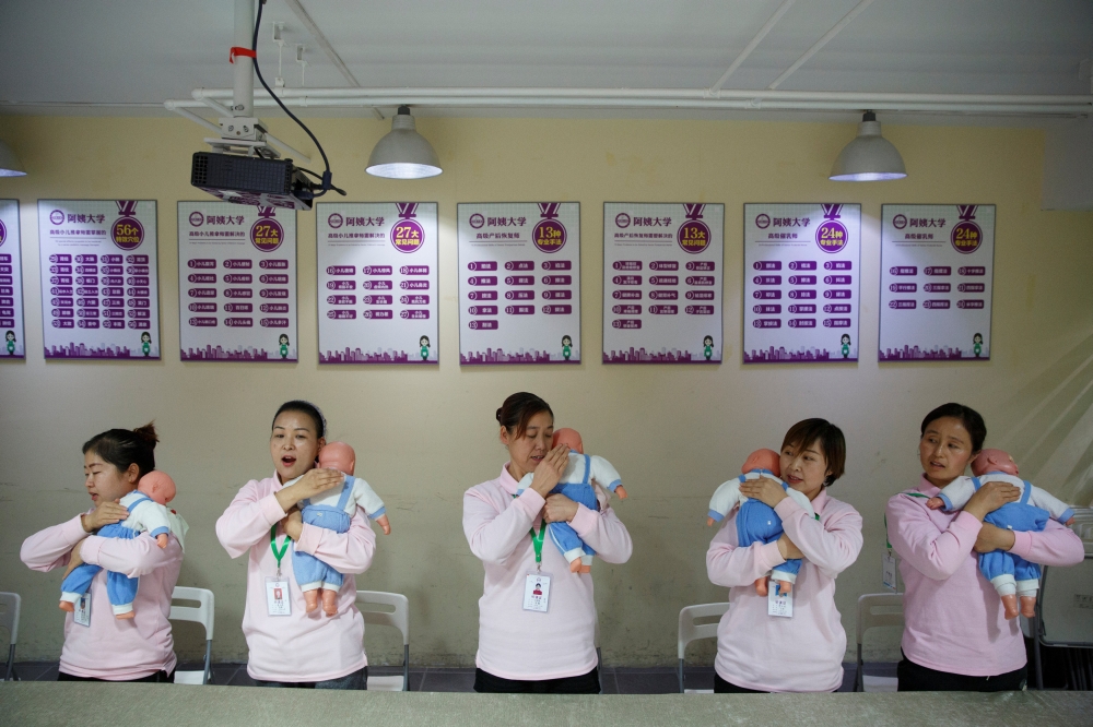 As part of a training program for domestic helpers, students at Ayi University practice on baby dolls during a course teaching childcare in Beijing. The training program teaches childcare, early education, housekeeping and other skills for domestic workers and is designed to meet the demand of China's middle class after the country scrapped the one-child policy. — Reuters