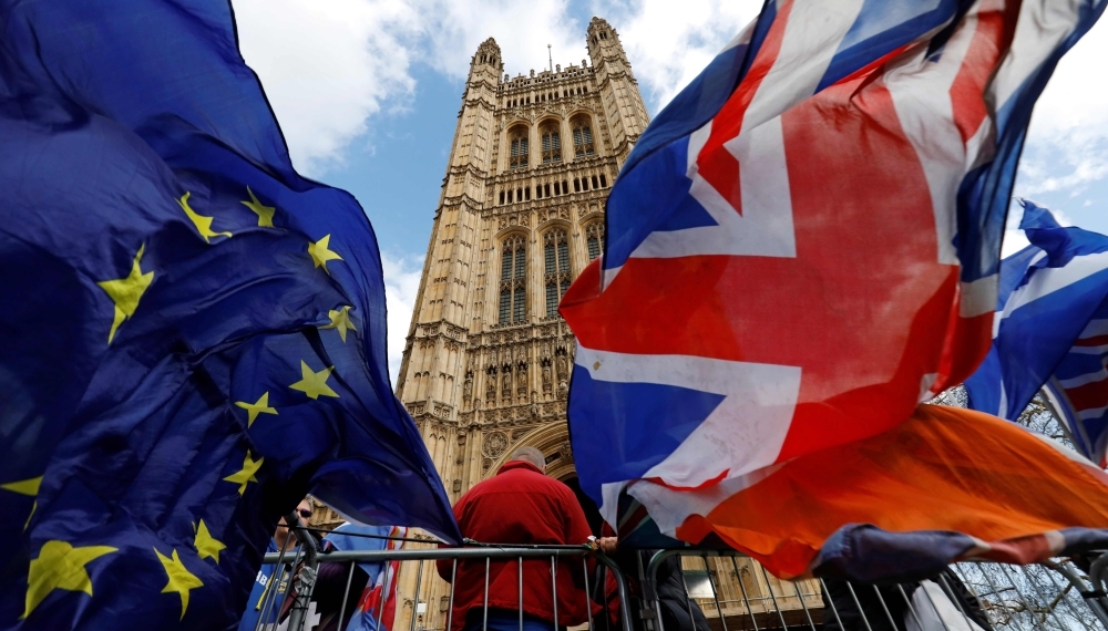 Pro- and anti-Brexit protesters hold flags as they demonstrate outside the Houses of Parliament in London on Thursday as members debate a motion on whether to seek a delay to Britain's exit from the EU. — AFP