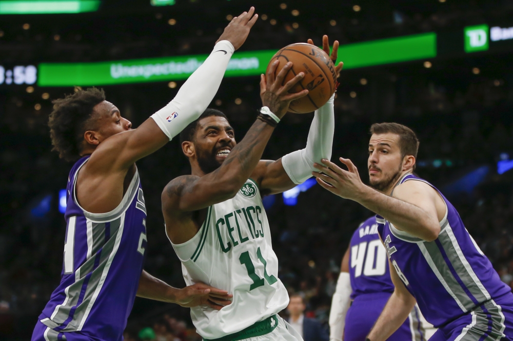 Boston Celtics guard Kyrie Irving (11) drives between Sacramento Kings guard Buddy Hield (24) and forward Nemanja Bjelica (88) during the second half at TD Garden. — Reuters