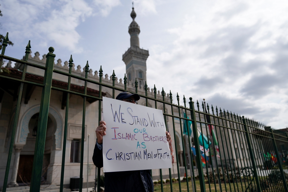 Gregory Glaros, from Arlington Virginia, holds a sign in solidarity with victims of the mass shootings at two mosques in New Zealand outside of the Islamic Center of Washington in Washington on Friday. — Reuters