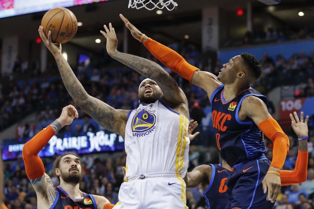 Golden State Warriors’ center DeMarcus Cousins (C) goes up for a basket as Oklahoma City Thunder’s guard Russell Westbrook (R) defends during their NBA game at Chesapeake Energy Arena in Oklahoma City Saturday. — Reuters 