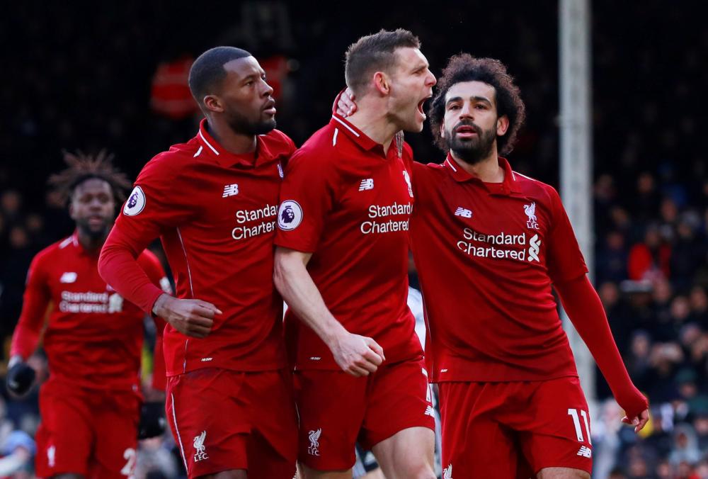 Liverpool's James Milner celebrates scoring their second goal from the penalty spot with Georginio Wijnaldum and Mohamed Salah during their Premier League match against Fulham at Craven Cottage, London, Sunday. — Reuters
