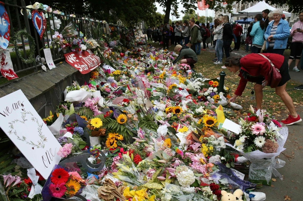 Residents look at flowers in tribute to victims in Christchurch on Monday, three days after a shooting incident at two mosques in the city. — AFP