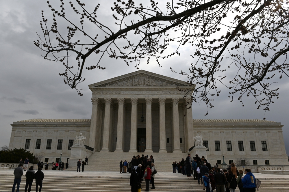 People wait in line outside the US Supreme Court to hear the orders being issued in Washington on Monday. — Reuters
