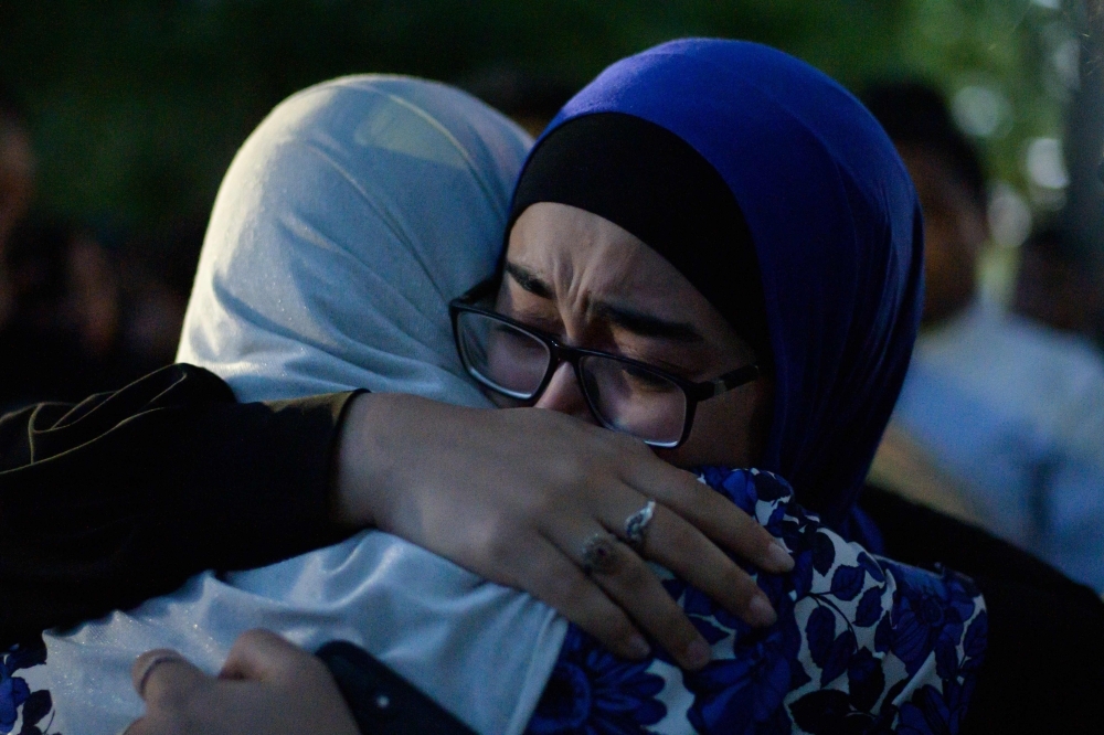 Two women cry and hug after watching a performance of the haka in front of the Al Noor mosque as a tribute to victims in Christchurch on Wednesday, five days after the twin mosque shootings claimed the lives of 50 people. — AFP