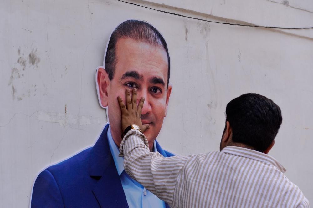 An Indian supporters of the Congress Party keeps his hand on the face of a cut out of billionaire jeweler Nirav Modi during a protest in New Delhi in this Feb. 16, 2018 file photo. — AFP