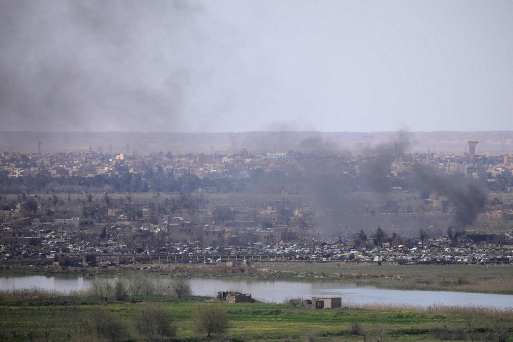 Smoke rises from the last besieged neighborhood in the village of Baghouz, Deir Al Zor province, Syria, on Wednesday. — Reuters