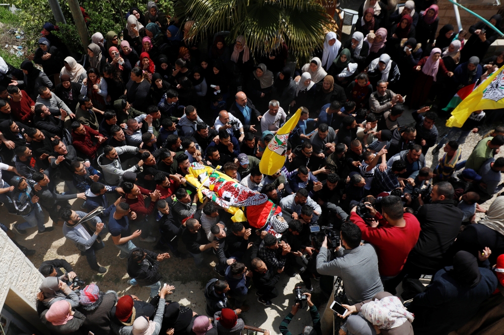  Mourners carry the body of Palestinian Ahmed Manasrah, during his funeral near Bethlehem, in the Israeli-occupied West Bank, on Thursday. — Reuters
