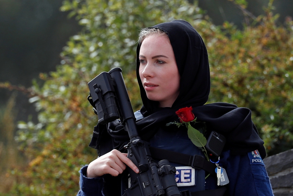 A policewoman is seen as people attend the burial ceremony of a victim of the mosque attacks, at the Memorial Park Cemetery in Christchurch, New Zealand, on Thursday. — Reuters