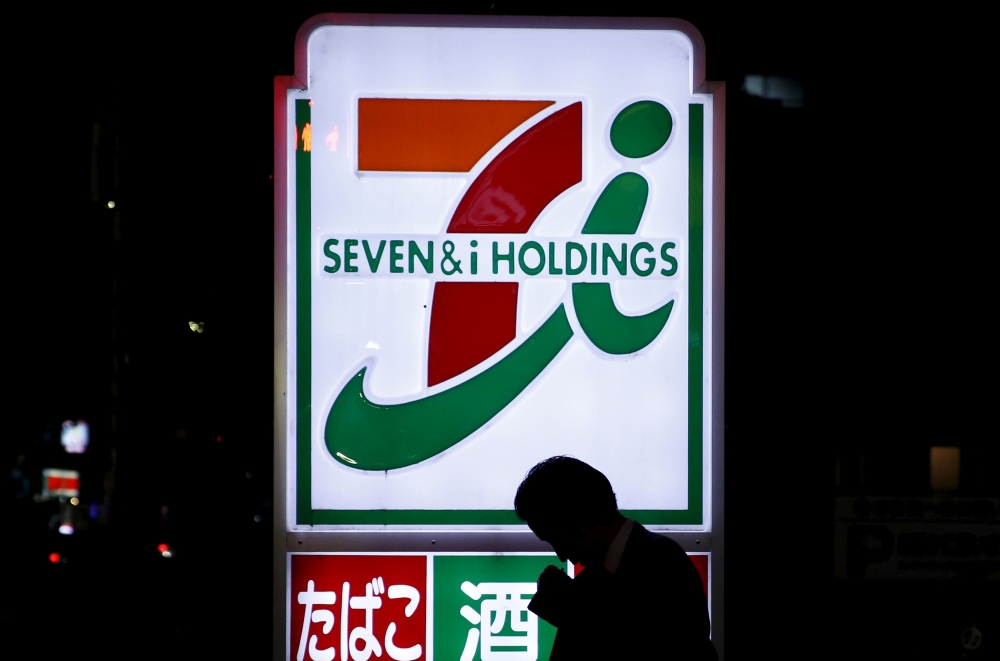 File photo shows a pedestrian walking in front of a signage of Seven & I Holdings' 7-Eleven convenience store in Tokyo, Japan. — Reuters
