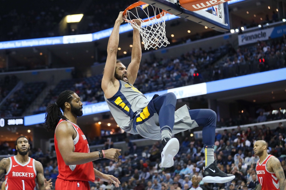 Memphis Grizzlies center Joakim Noah (55) hangs on the rim after dunking the ball as Houston Rockets center Nene (42) looks on at FedExForum. Memphis won 126-125. — Reuters